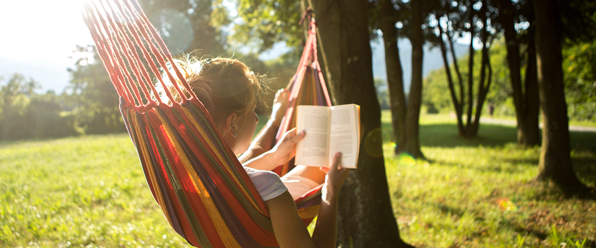 Eine Frau liest ein Buch in der Hängematte an einem Sommertag